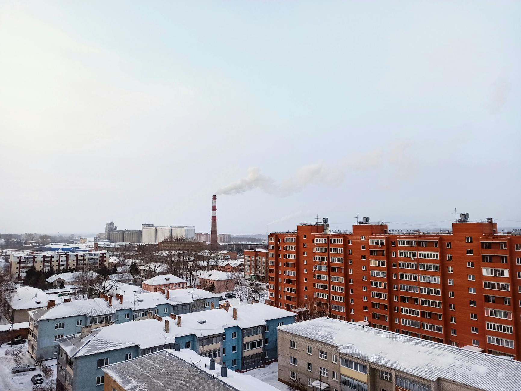 Zimowe miasto z zaśnieżonymi dachami i dymem unoszącym się z kominów