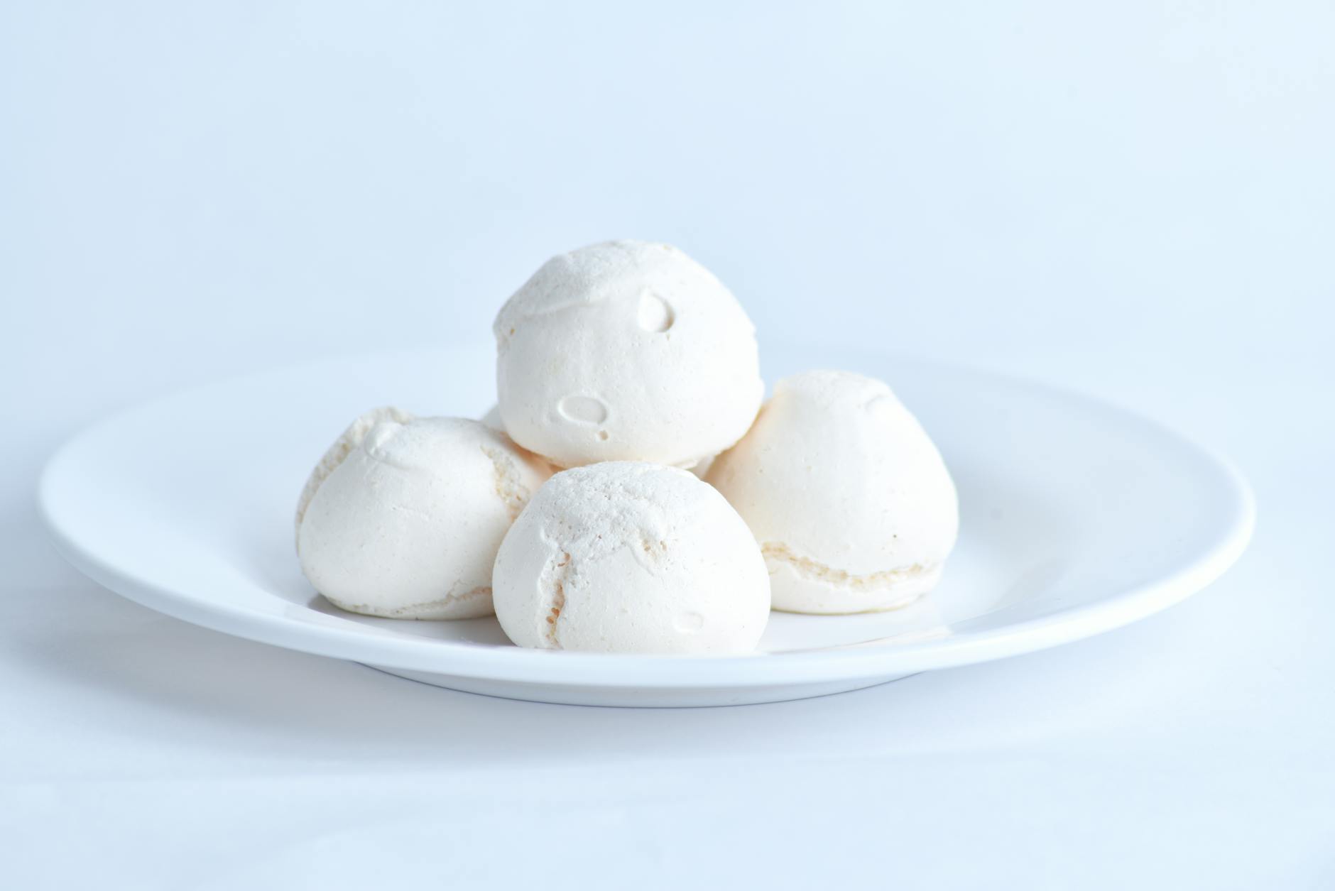 Białe bezy ułożone na ceramicznym talerzu z bliska