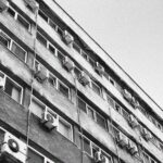 Blok z wielkiej płyty z licznymi klimatyzatorami na elewacji